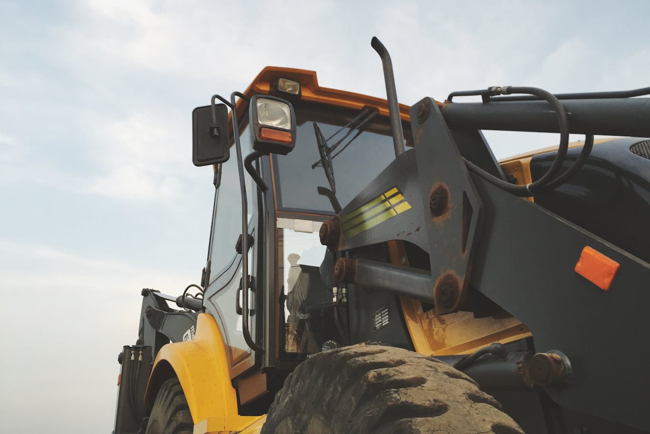 Detailed view of a yellow excavator against a clear sky at a construction site.